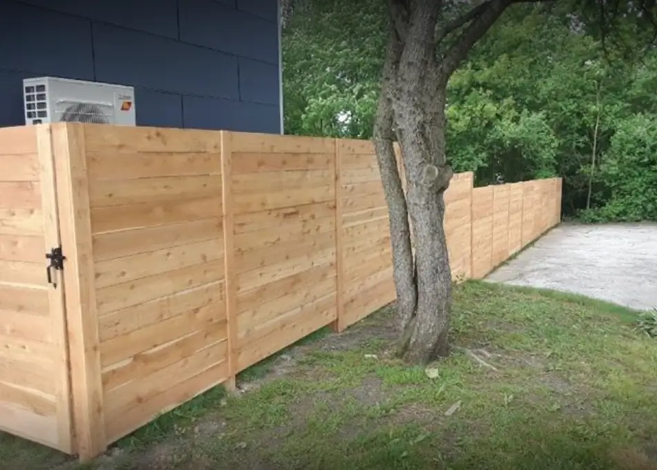 A wooden fence in front of a tree.