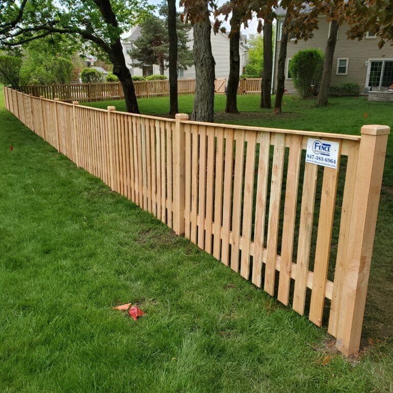 A wooden fence in a yard with grass.