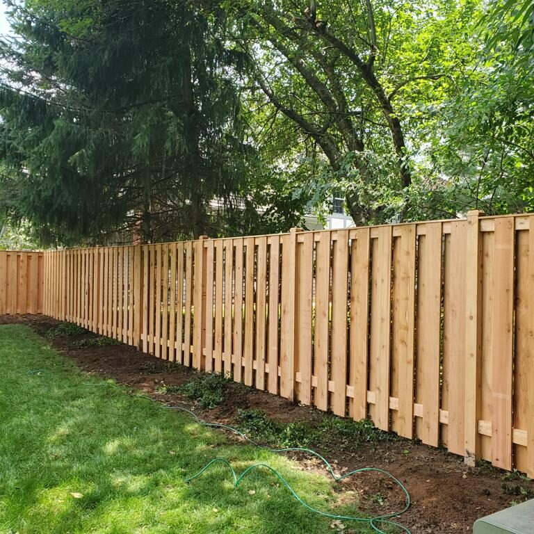A wooden fence is being installed in a backyard.