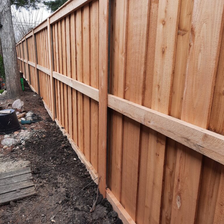 A wooden fence is being built in a backyard.