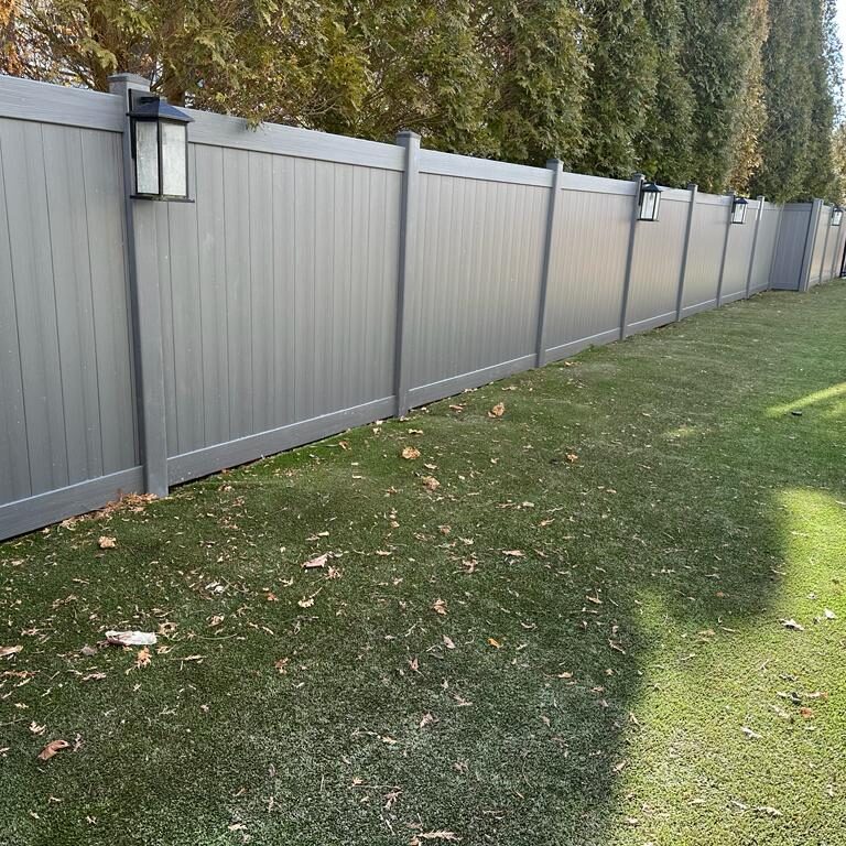 A backyard with a gray fence and grass.