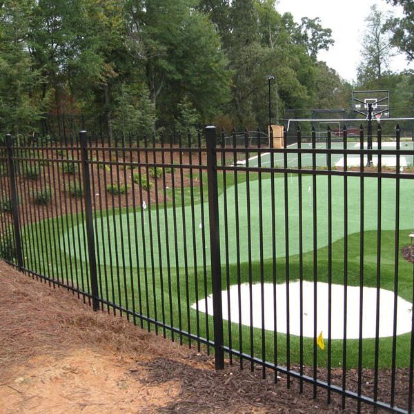 A black wrought iron fence with a golf course in the background.