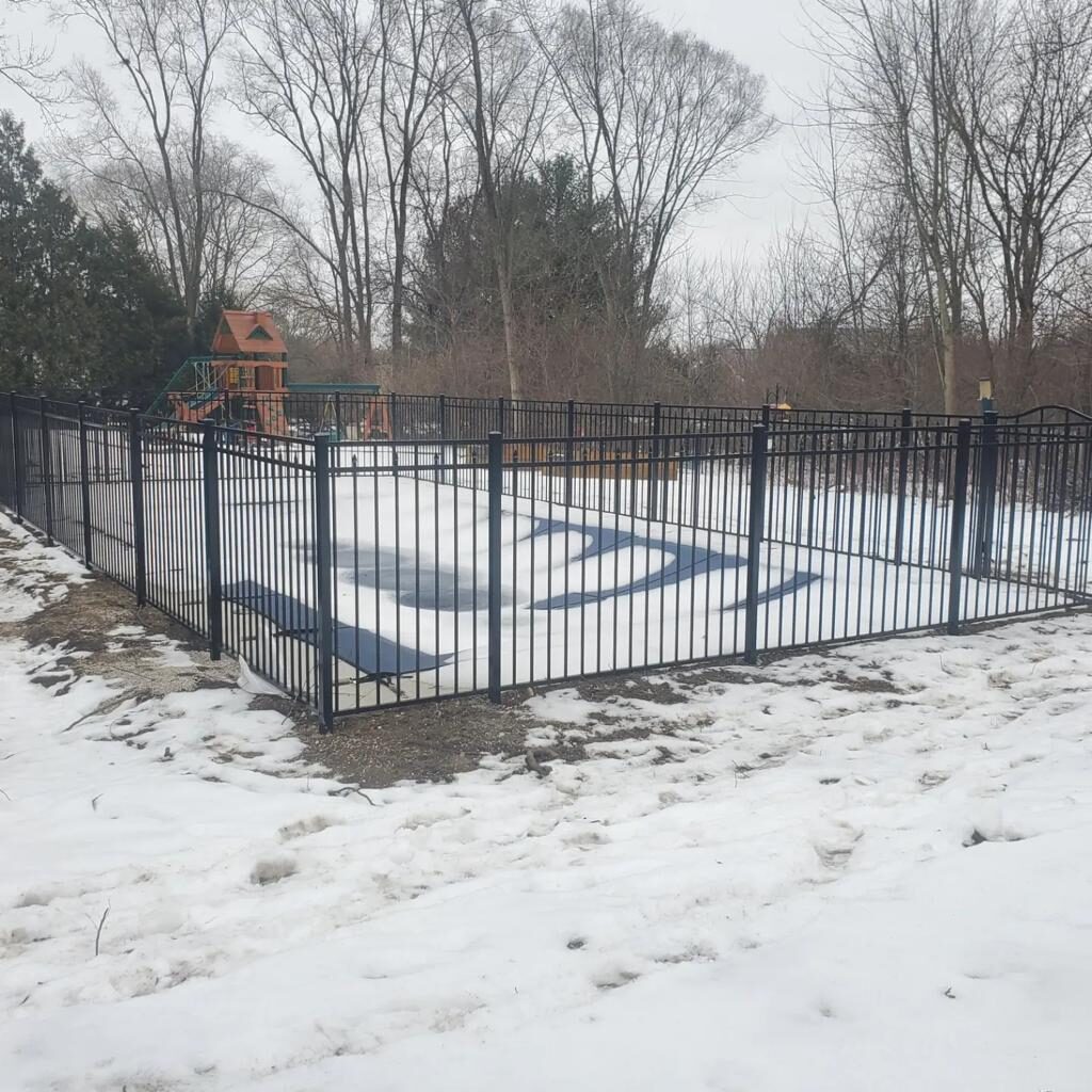 A pool with a black fence in the snow.